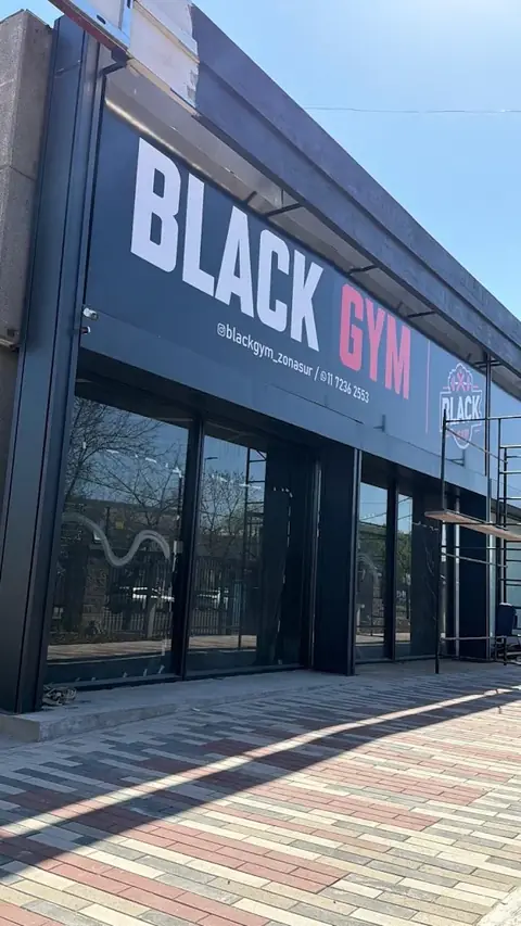 Fachada de un gimnasio con cartel grande y vidrieras
